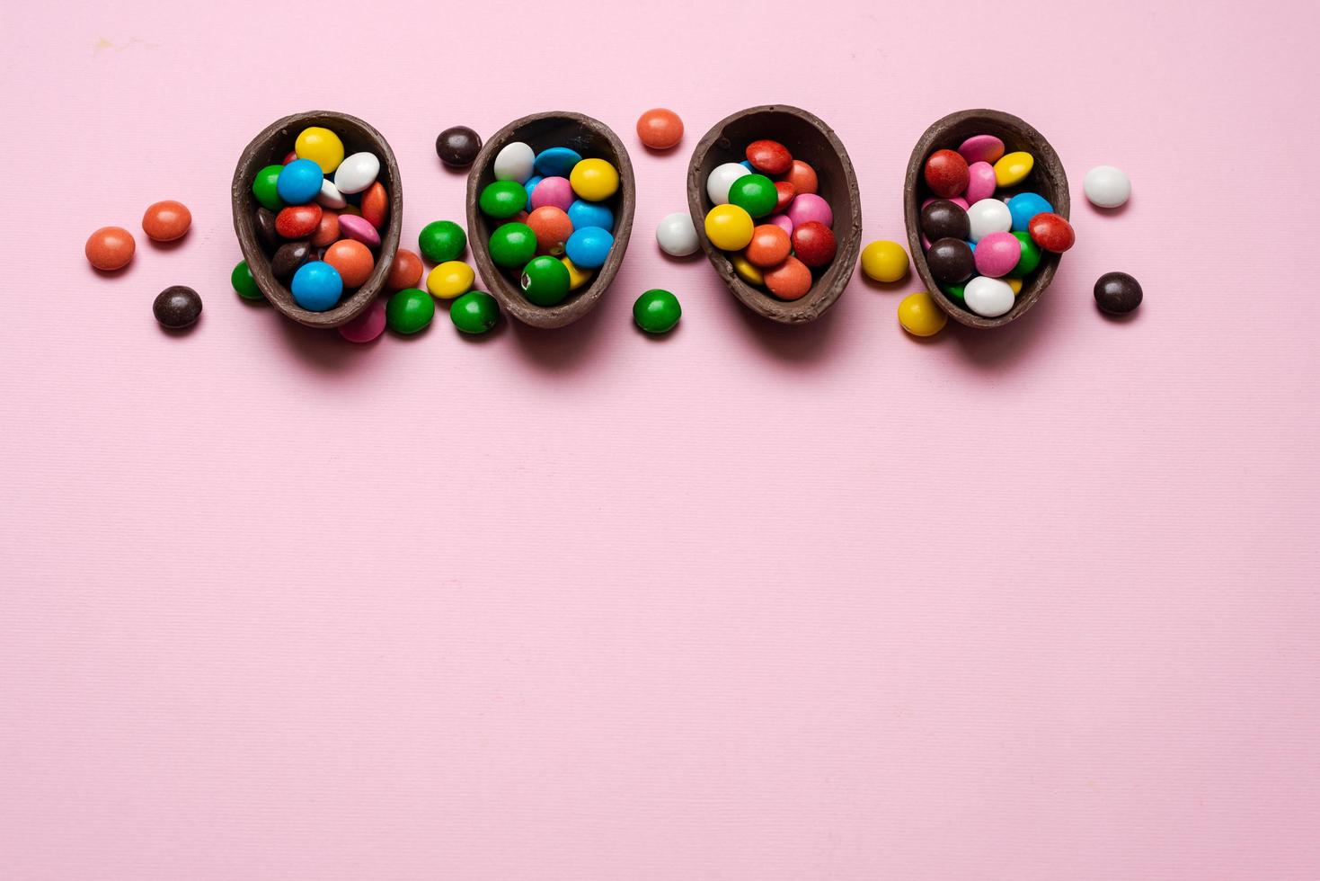 vrolijk Pasen overhead met chocolade paaseieren en decoraties op een roze achtergrond met kopieerruimte. foto