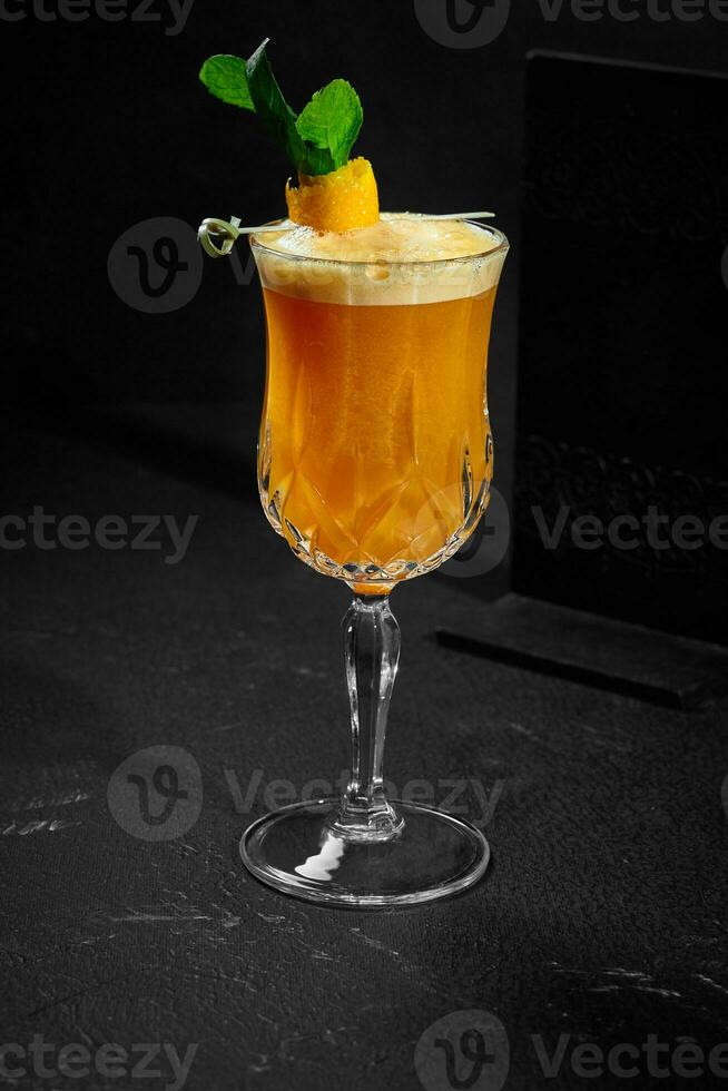 verfrissend orangeade met vers munt in glas Aan zwart achtergrond foto