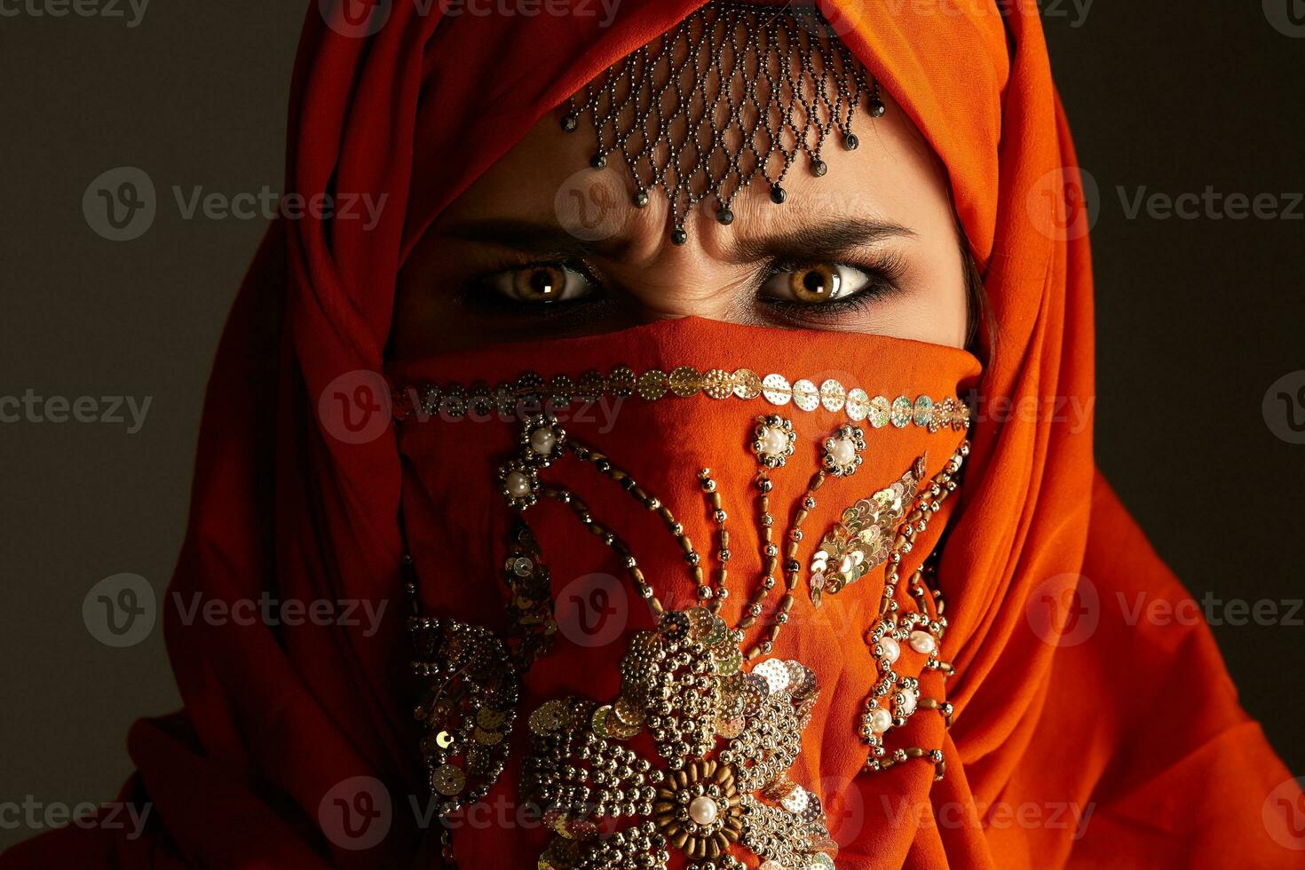 studio schot van een jong charmant vrouw vervelend de terracotta hijab versierd met pailletten en sieraden. Arabisch stijl. foto