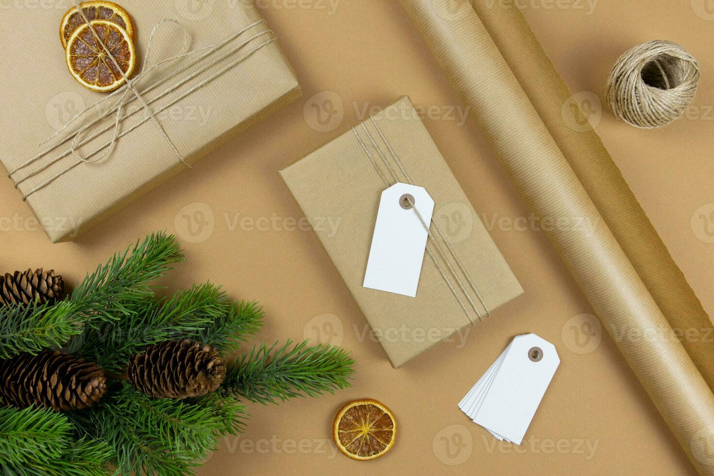 Kerstmis handgemaakt geschenk dozen met etiket label model, pijnboom kegels, Spar boom takken en decoratie Aan ambacht papier achtergrond. feestelijk gestileerd samenstelling. top visie. foto