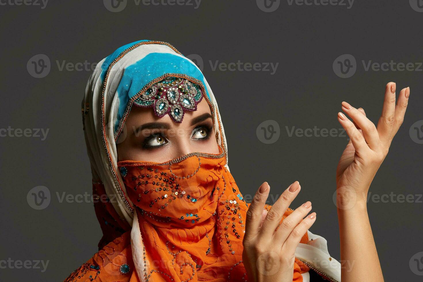 studio schot van een verchroomd vrouw vervelend de kleurrijk hijab versierd met pailletten en sieraden. Arabisch stijl. foto