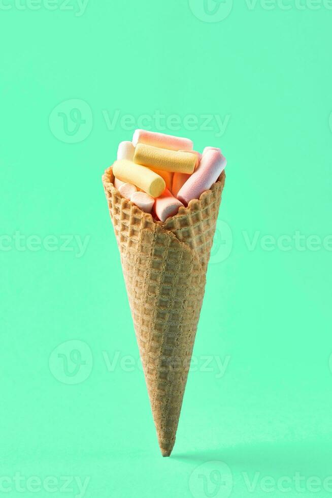 roze en geel marshmallows in wafel ijshoorntje Aan licht groen achtergrond. vrij ruimte voor uw tekst foto