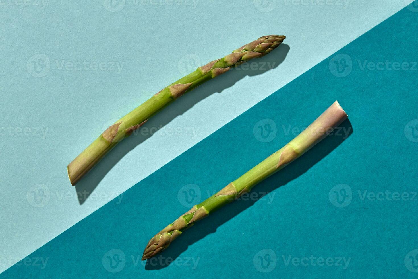 twee groen asperges speren Aan kleurrijk achtergrond. concept van gezond voedsel en Bijsnijden van voorjaar groenten. dichtbij omhoog, kopiëren ruimte foto