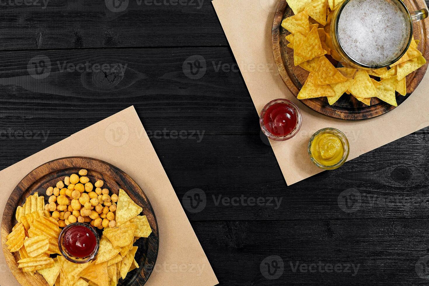 lager bier en snacks Aan zwart houten tafel. noten, chips. top visie met copyspace foto