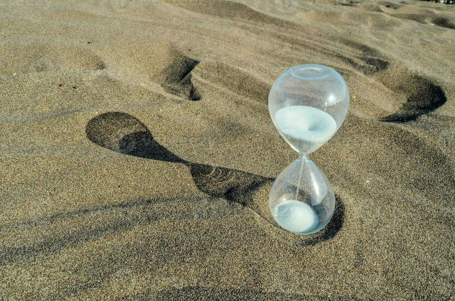 een zandloper zittend Aan de zand in de midden- van de zand foto