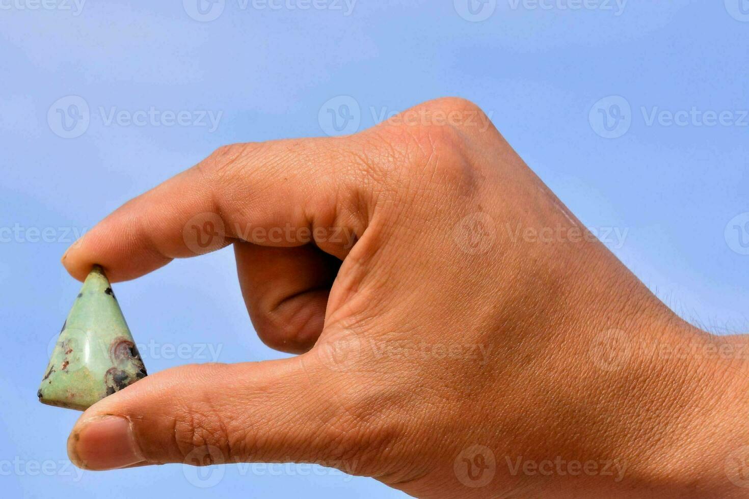 een persoon Holding een klein groen steen in hun hand- foto