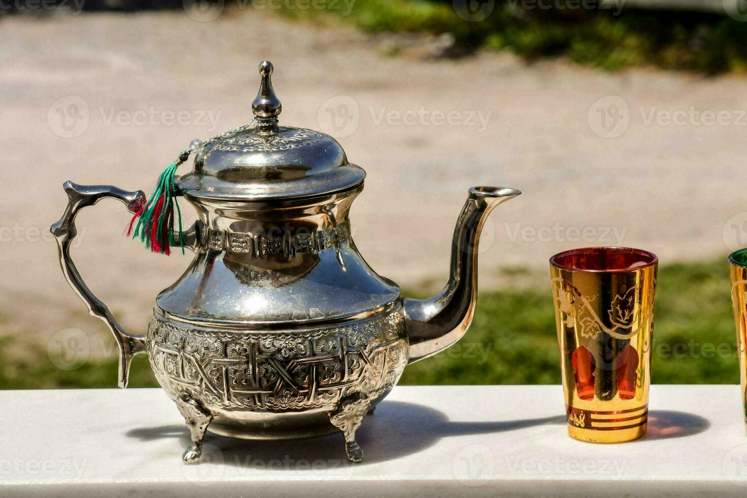 een zilver thee pot en twee cups Aan een tafel foto