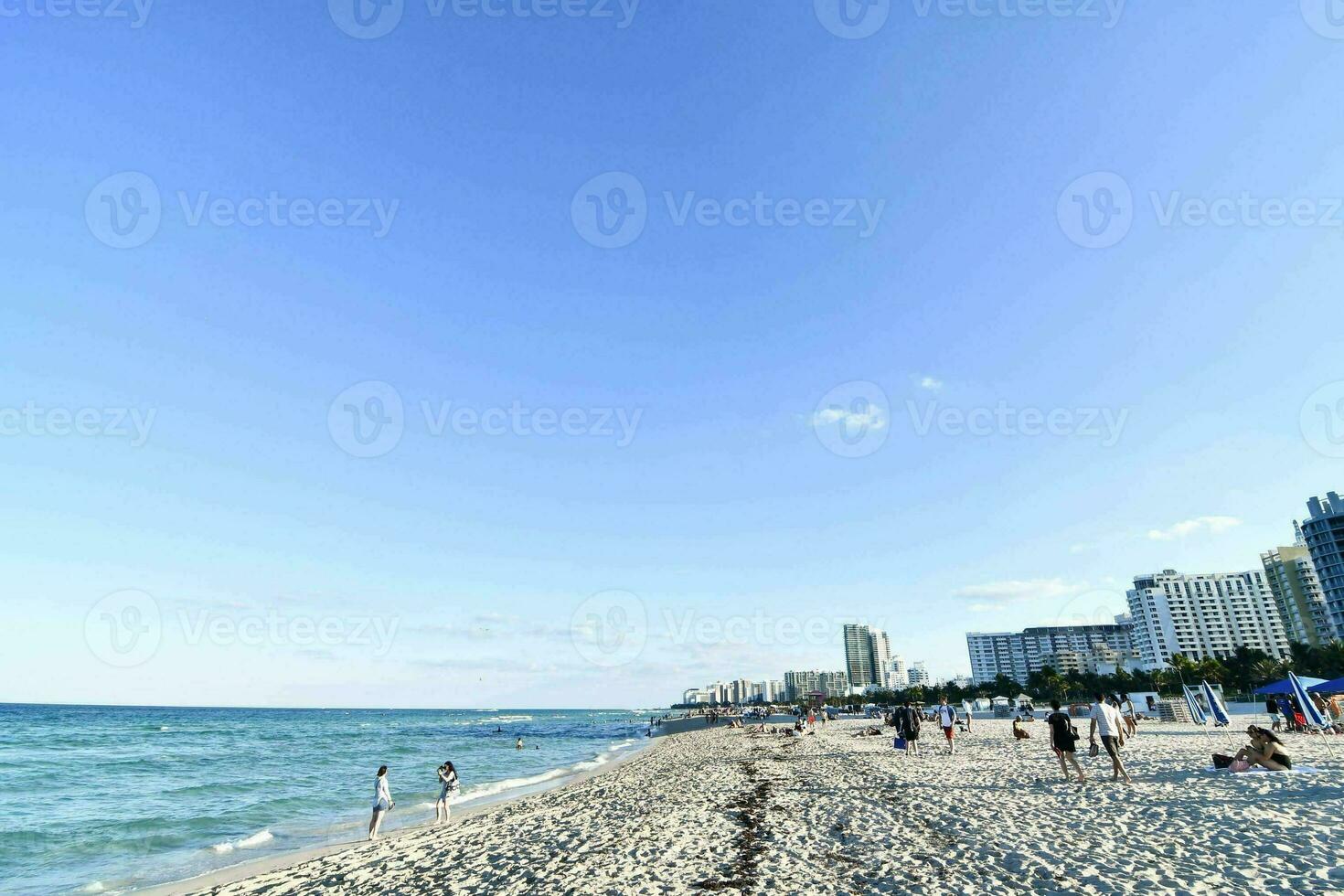 een strand met mensen Aan het en gebouwen in de achtergrond foto