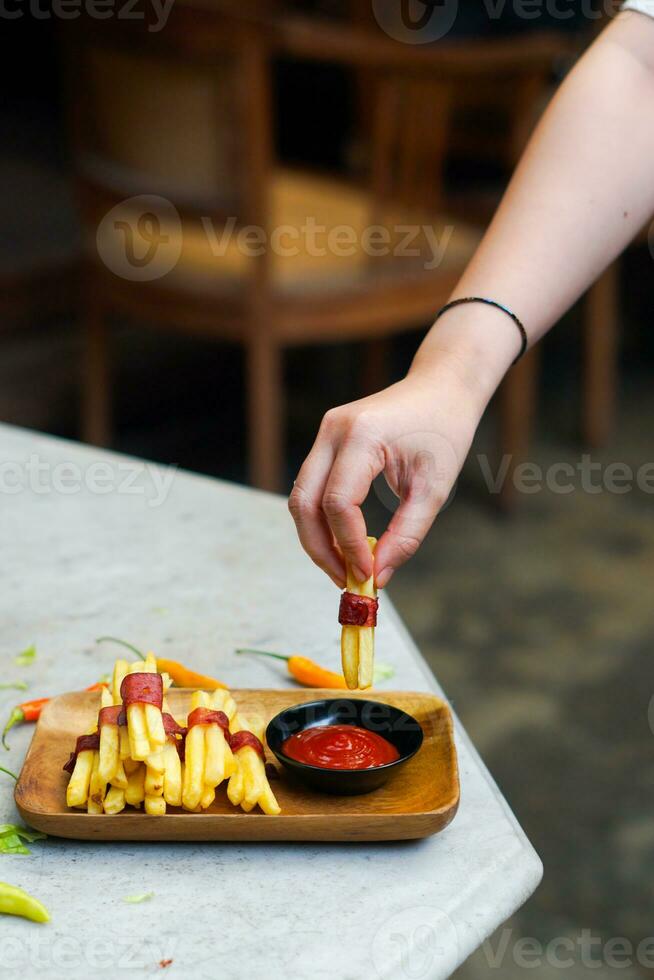 bijgesneden hand- dompelen aardappel plak naar saus dichtbij omhoog foto