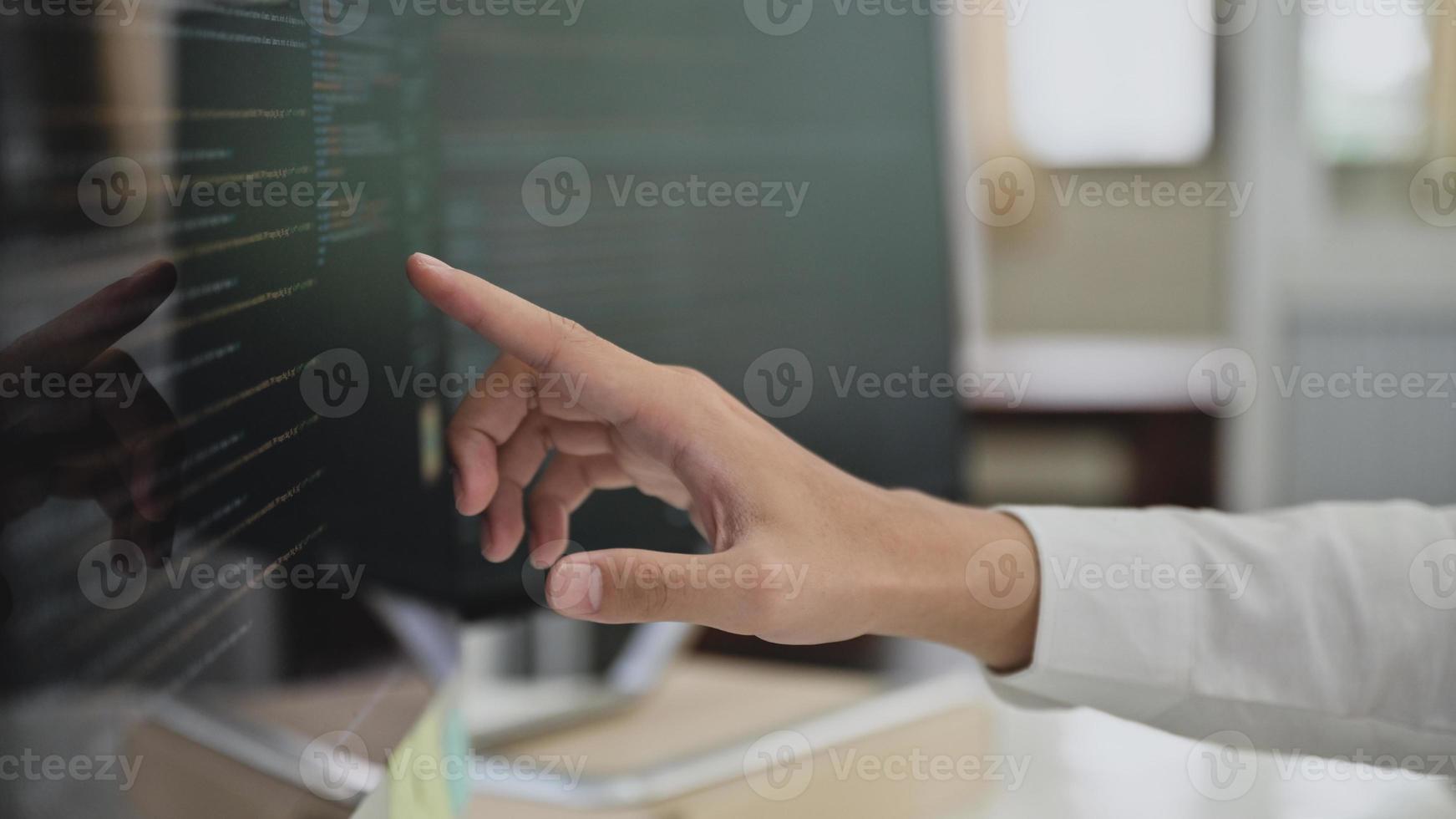 close-up shot van programmeurs die met de vinger wijzen naar de code op een computerscherm. foto