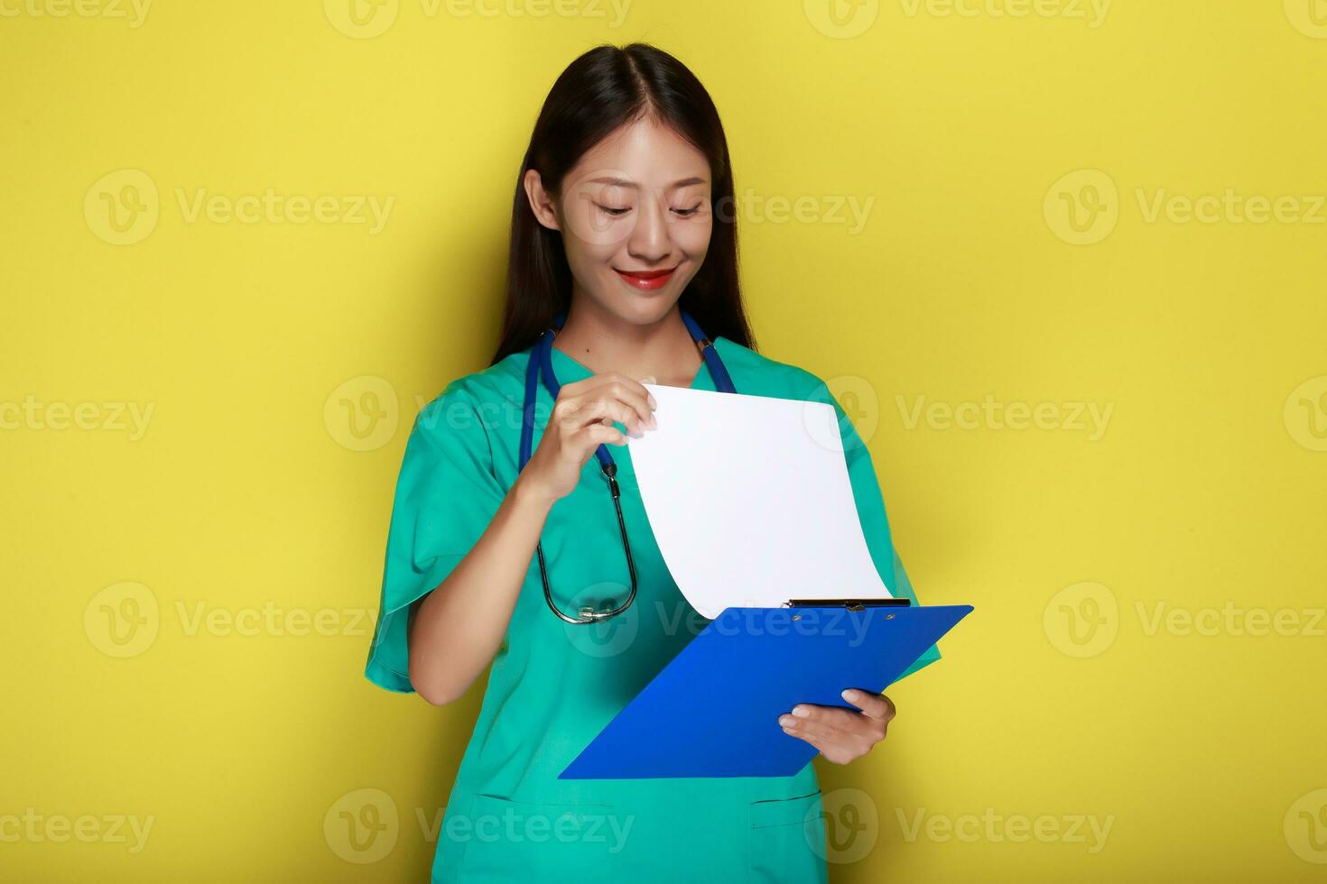 mooi jong vrouw maakt een attent uitdrukking terwijl vervelend een dokter uniform staand in voorkant van een geel achtergrond. foto