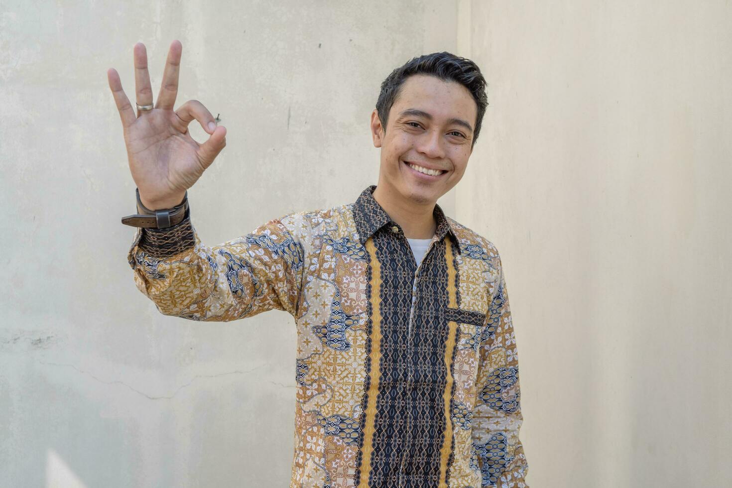 jong Indonesisch slijtage batik traditioneel cultuur van Indonesië met OK gebaar. foto