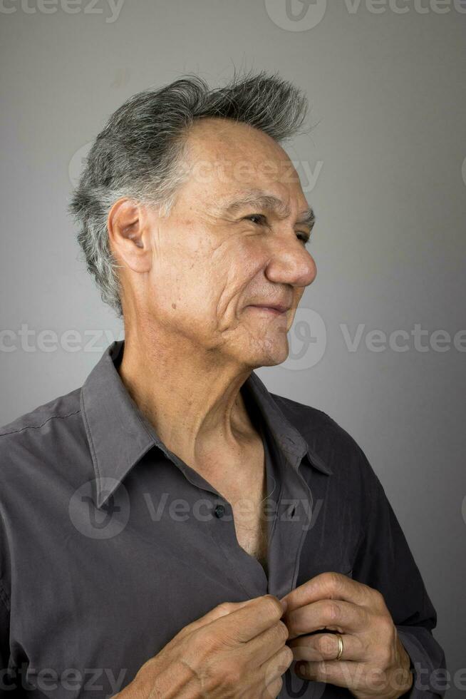 volwassen senior Mens knopen omhoog zijn overhemd terwijl krijgen jurk voor werk foto