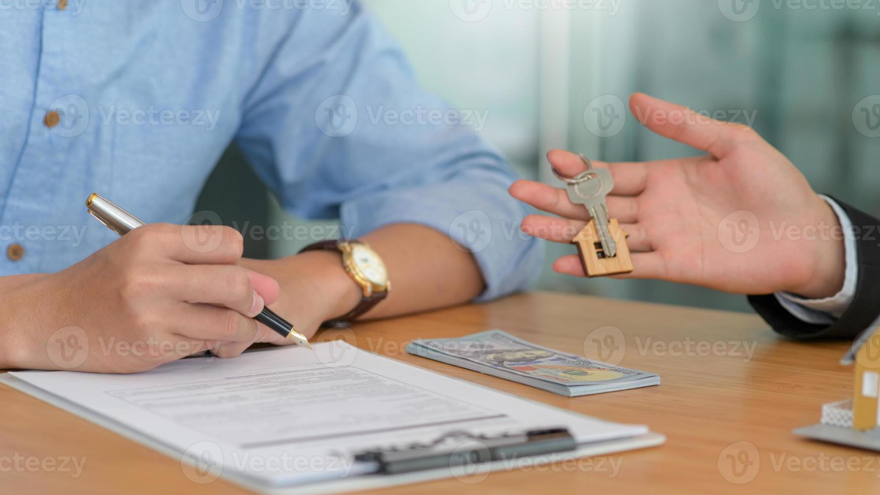 het tekenen van een contract en het afleveren van de huissleutels voor het kopen en verkopen van huizen. foto