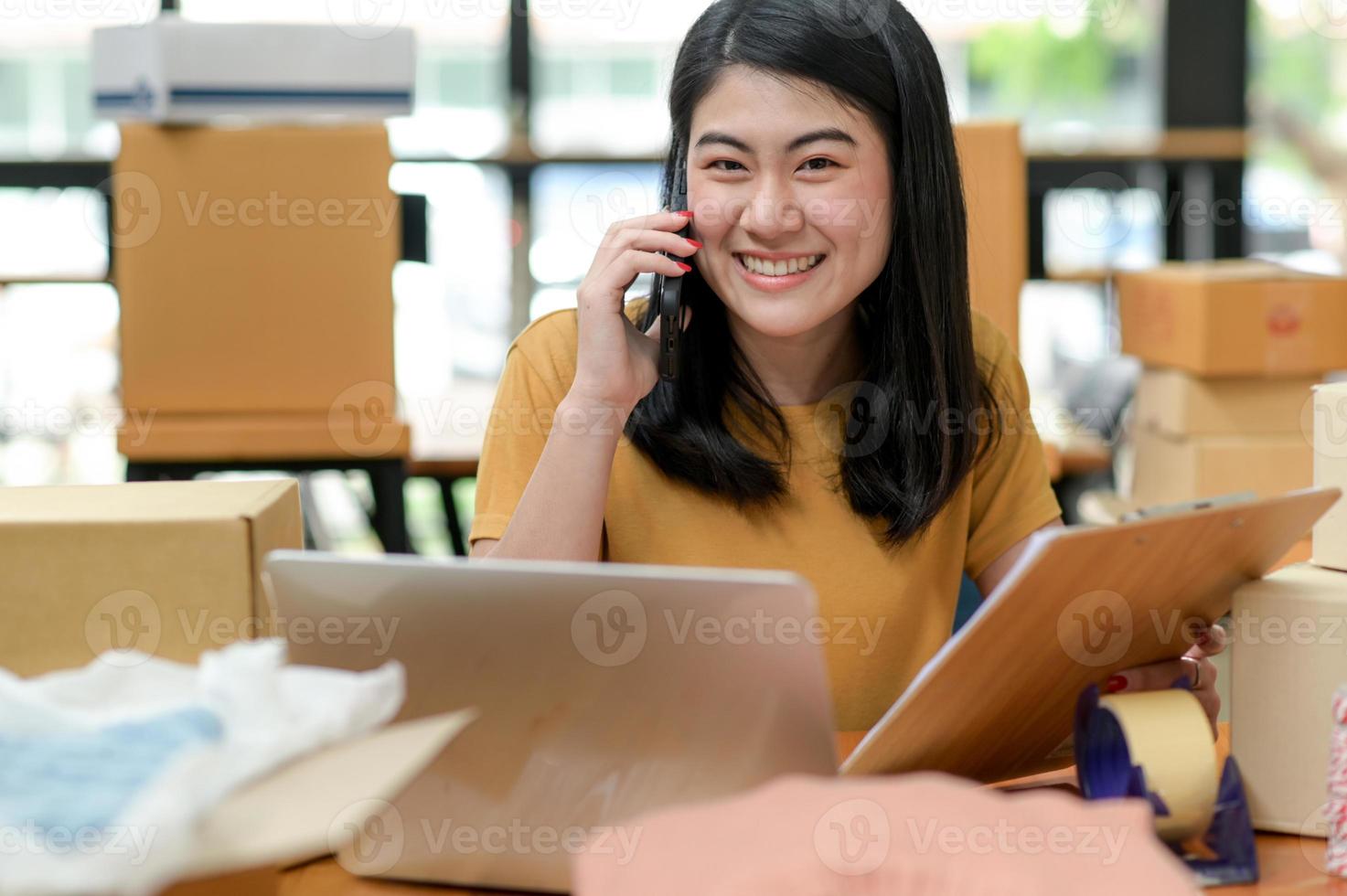 een vrouw die een online product verkoopt, praat aan de telefoon voor informatie en houdt een klantendossier bij. foto