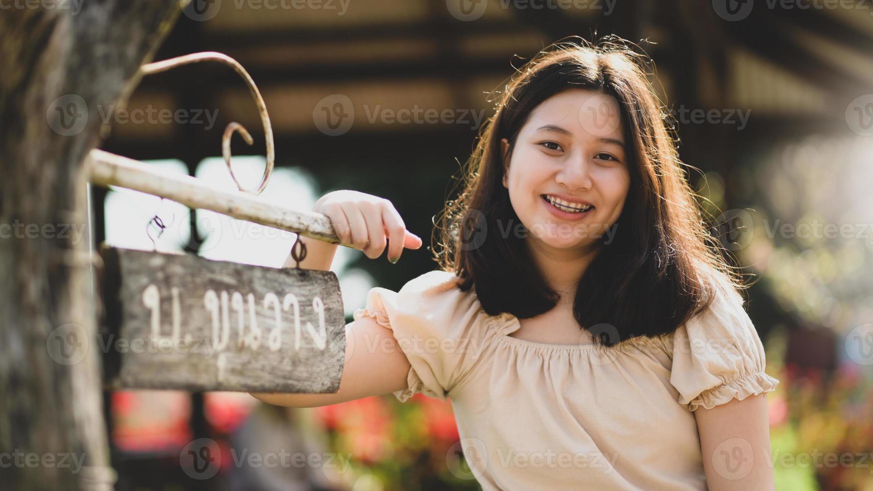 Aziatische tienermeisje geconfronteerd met de camera glimlachend gelukkig als ze in de natuur reist. foto