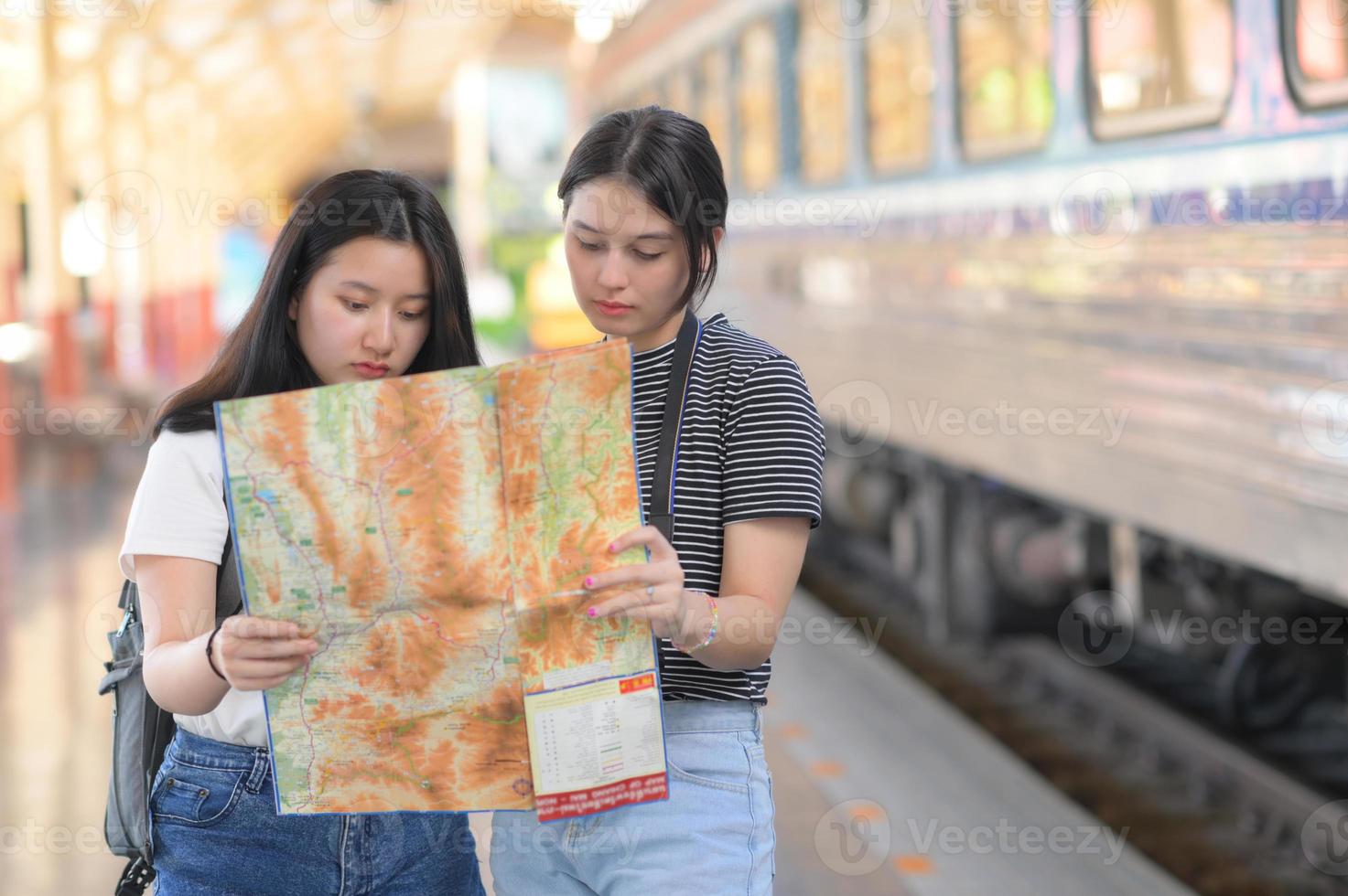 twee tienermeisjes kijken naar kaarten om met de trein te reizen. foto