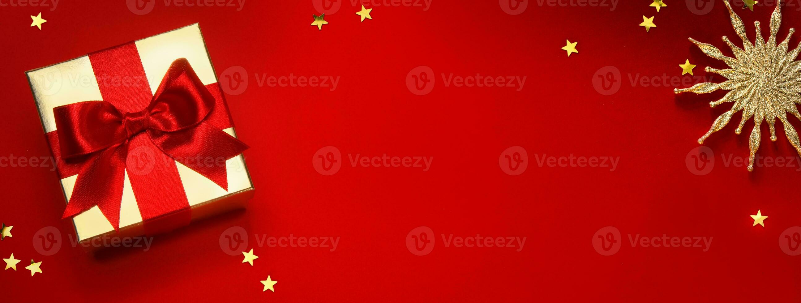 Kerstmis banier of groet kaart achtergrond met Kerstmis geschenk doos en gouden decoratie Aan rood achtergrond foto