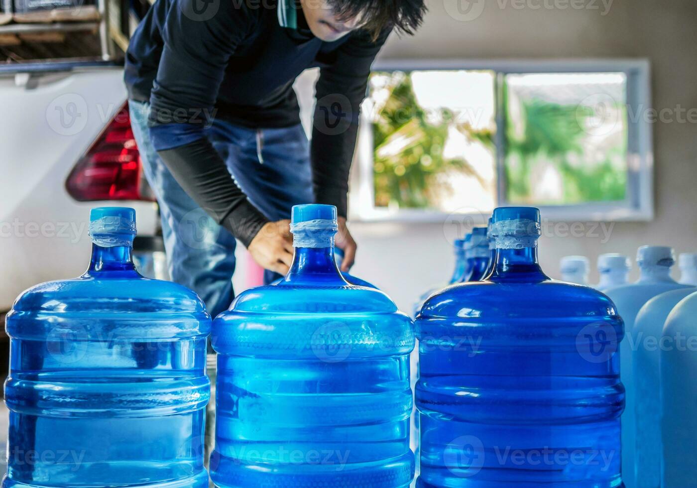 drinken water Doorzichtig en schoon in blauw gallon geregeld in een rij bereiden naar optillen in de terug van een vervoer vrachtauto gezuiverd drinken water binnen de productie lijn klein bedrijf foto