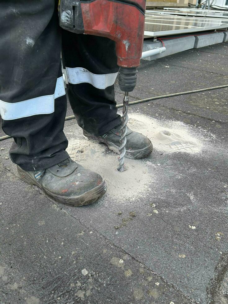 bouw arbeider behandeling een boren naar maken een gat in een beton vloer. foto
