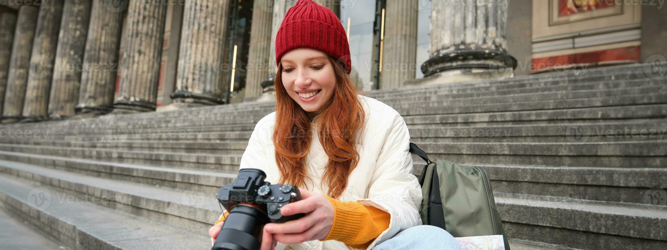 jong leerling, fotograaf zit Aan straat trap en cheques haar schoten Aan professioneel camera, nemen foto's buitenshuis foto