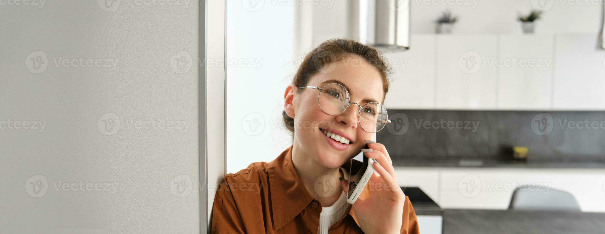 portret van gelukkig glimlachen jong vrouw Bij huis, pratend Aan mobiel telefoon, roeping vriend en hebben mooi hoor gesprek, antwoord telefoon foto