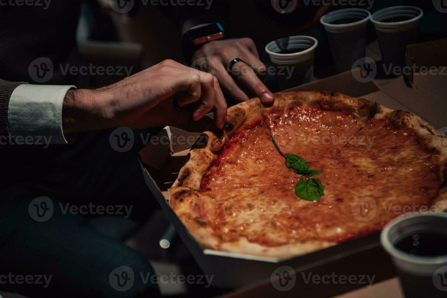 een Mens is snijdend een pizza in stukken foto