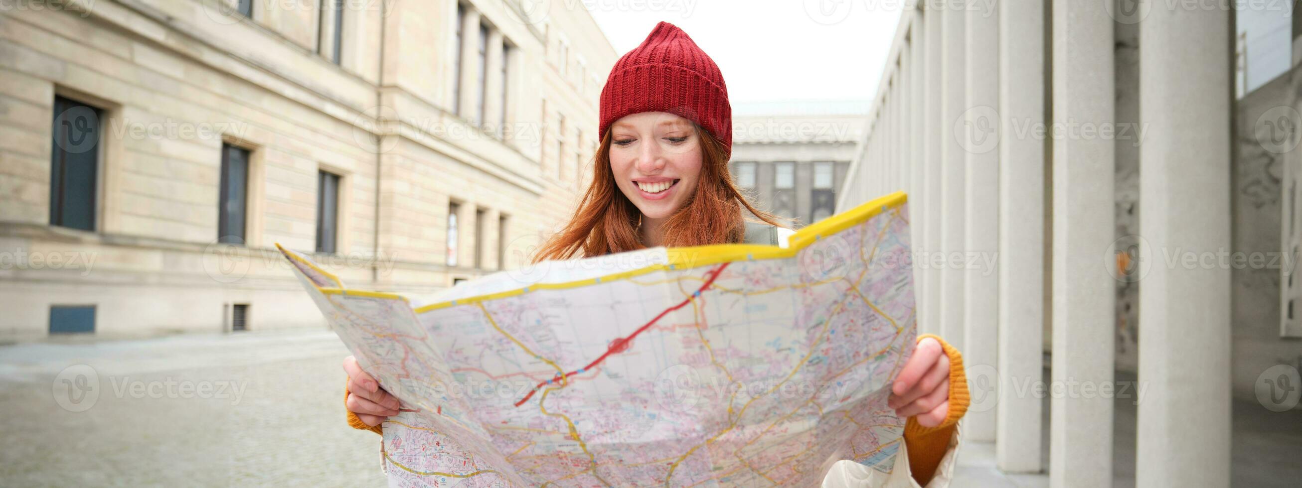 roodharige meisje, toerist onderzoekt stad, looks Bij papier kaart naar vind manier voor historisch oriëntatiepunten, vrouw Aan haar reis in de omgeving van Europa zoekopdrachten voor bezienswaardigheden bekijken foto