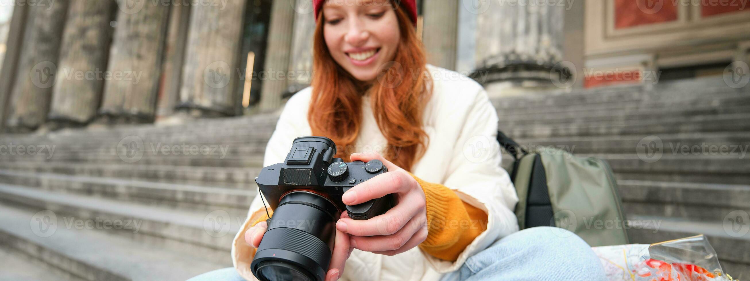 jong leerling, fotograaf zit Aan straat trap en cheques haar schoten Aan professioneel camera, nemen foto's buitenshuis foto