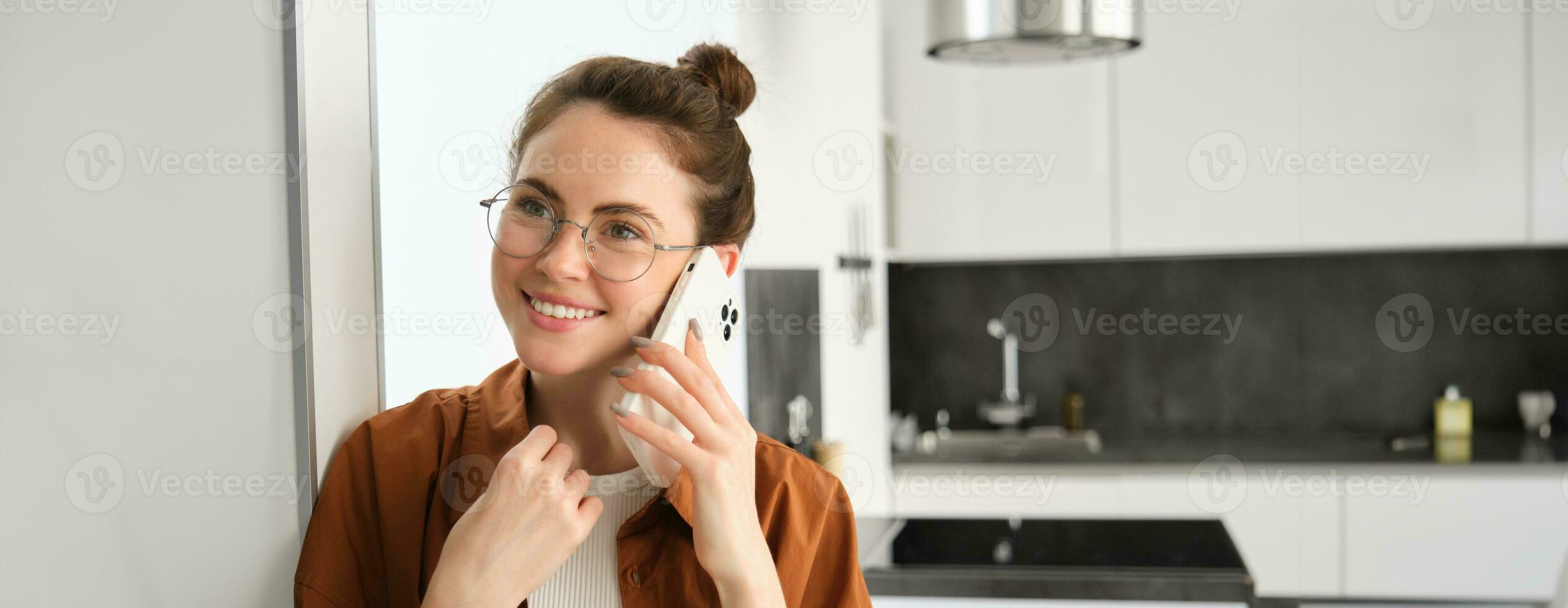 portret van gelukkig glimlachen jong vrouw Bij huis, pratend Aan mobiel telefoon, roeping vriend en hebben mooi hoor gesprek, antwoord telefoon foto