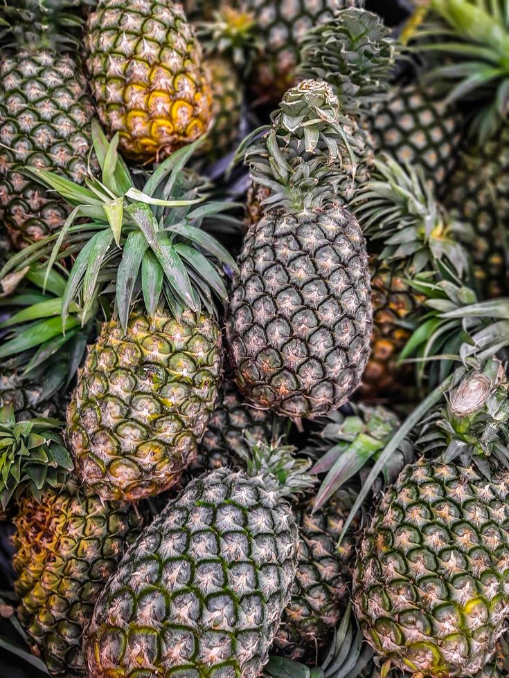 veel ananas fruit achtergrond, tropisch fruit te koop foto