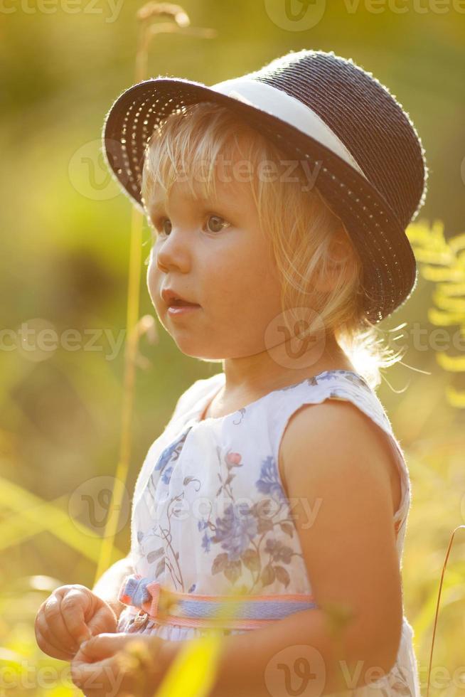 klein blond meisje in jurk en hoed foto