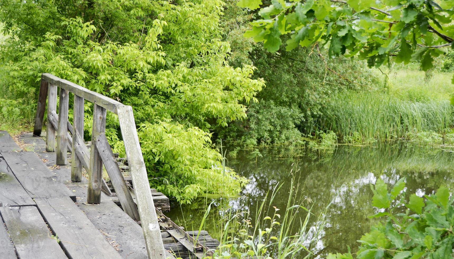 prachtig staande oude houten brug over rivier in gekleurde achtergrond foto