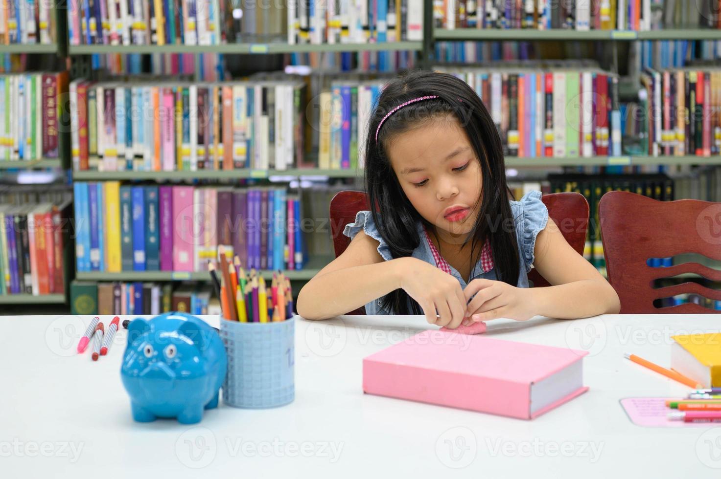 Aziatisch meisje vouwen en knutselen papier in bibliotheek tijdens kunstles. onderwijs en activiteitenconcept foto