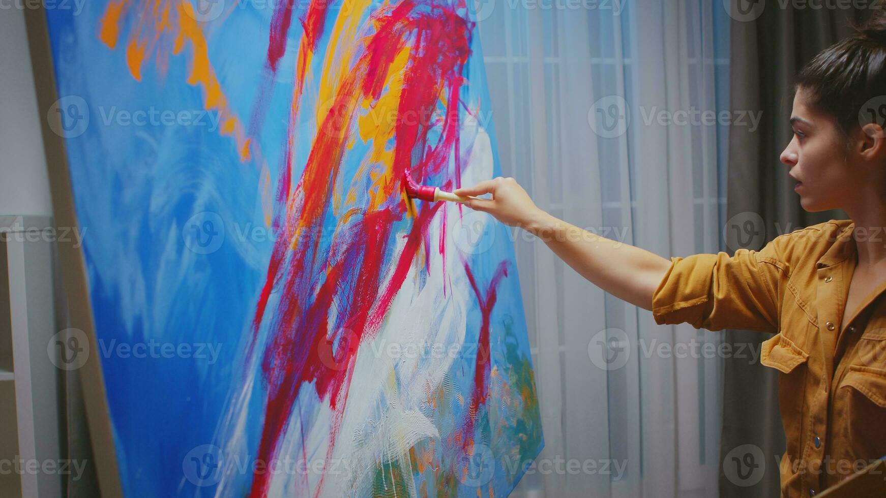 geslaagd jong vrouw schilderij in haar huis studio. foto