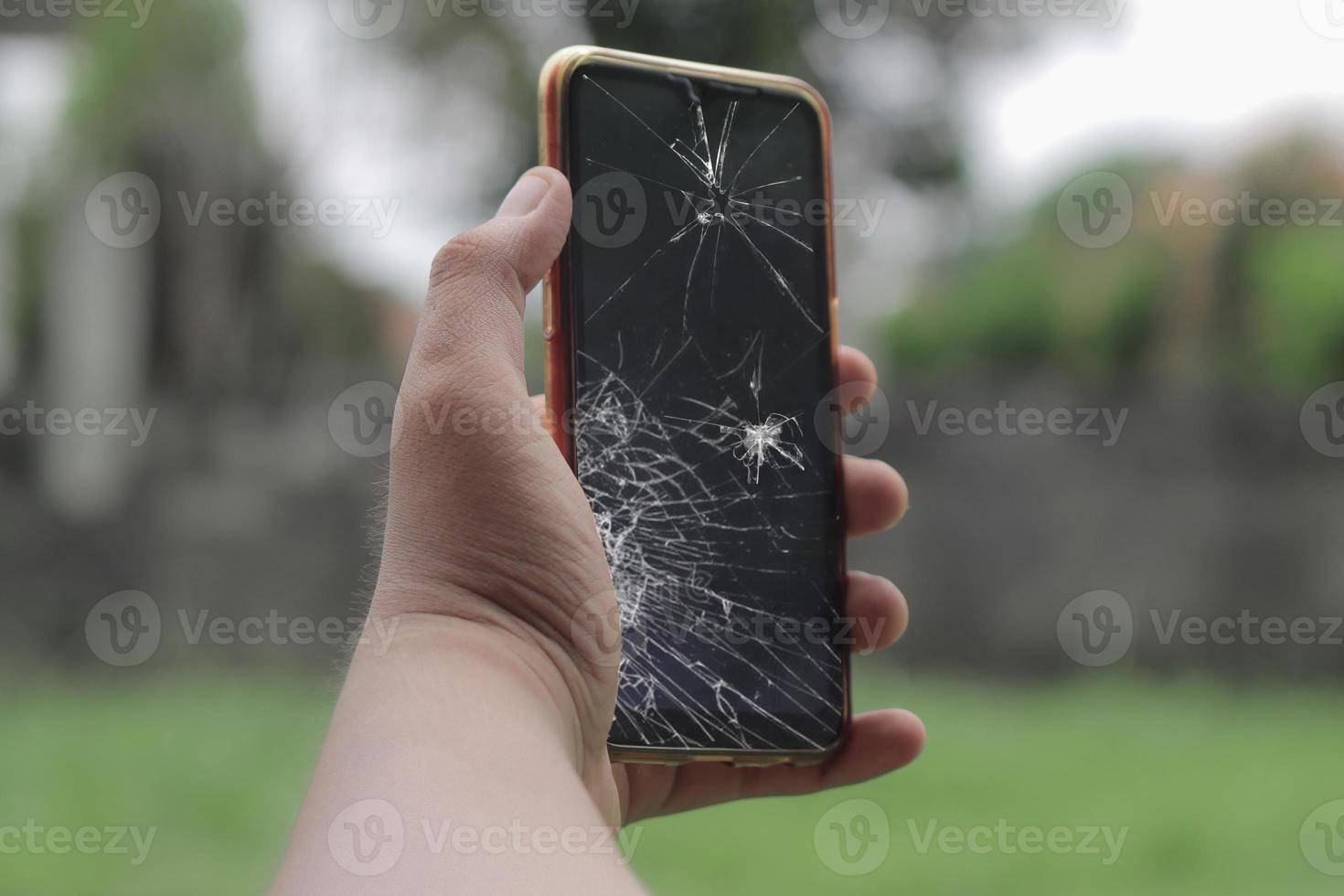 hand met gebroken lcd-glas van mobiele telefoon gebarsten en gebroken foto