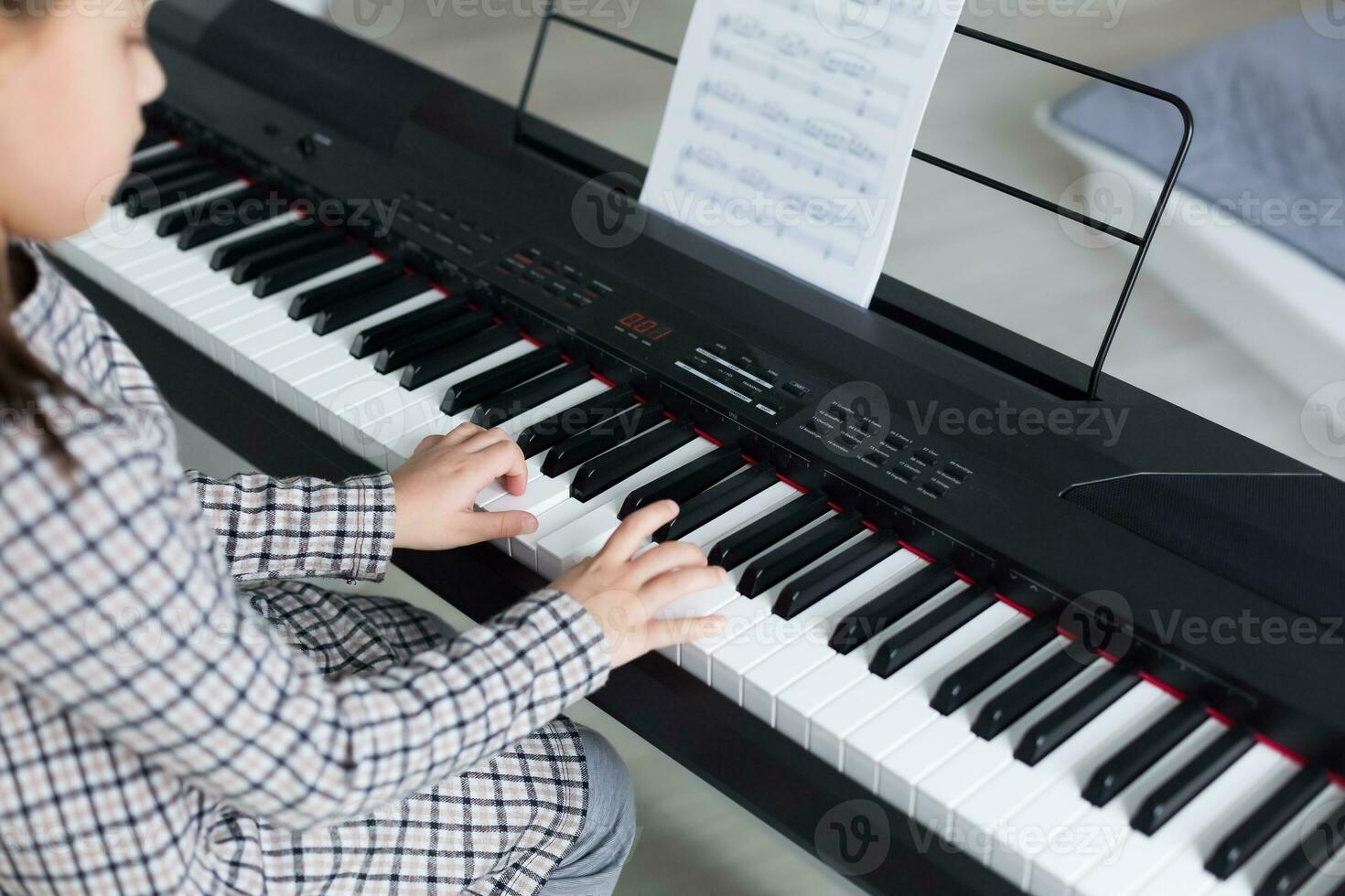 schattig weinig meisje Toneelstukken Aan piano, synthesizer. opleiding. onderwijs. school. esthetisch opleiding. elementair klas. foto