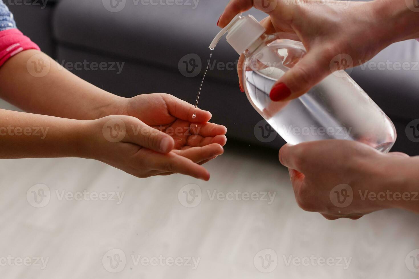 dichtbij omhoog moeder is van toepassing ontsmettingsmiddel naar haar dochter naar voorkomen infectie. familie hygiëne concept. foto