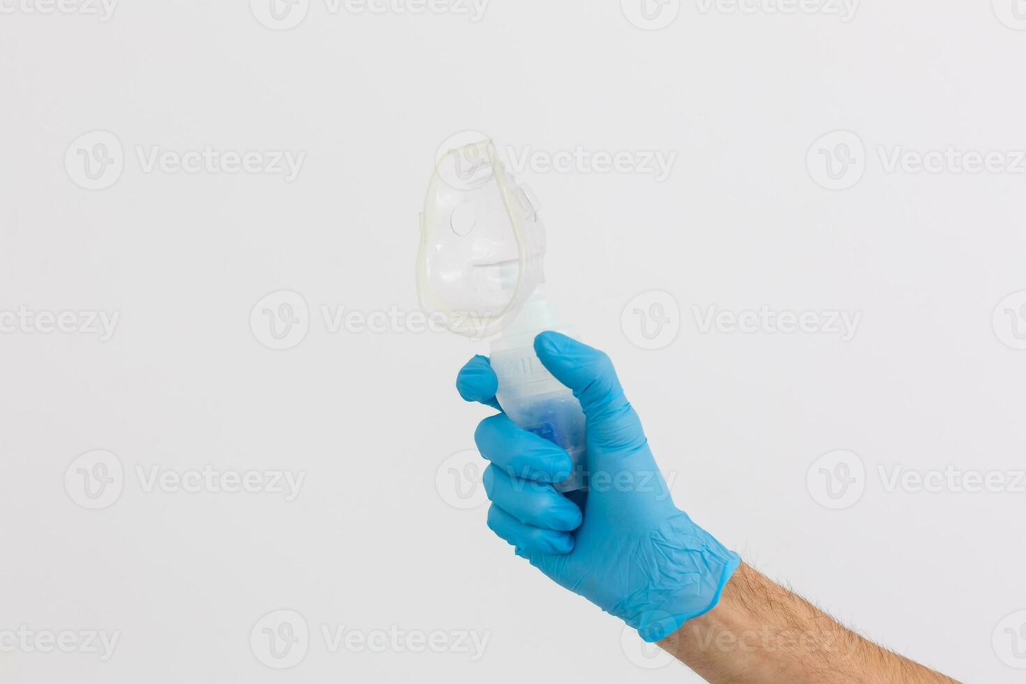 hand- in blauw beschikbaar medisch handschoen houdt vernevelaar drug reservoir met siliconen masker, inademing apparaat, longziekten concept, blauw achtergrond, kopiëren ruimte foto