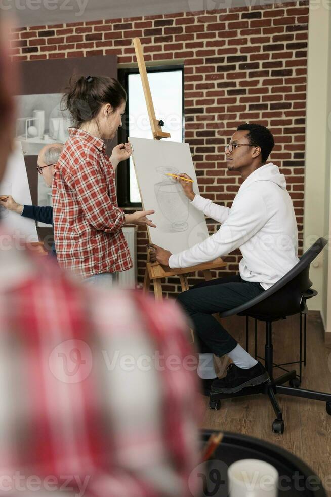 jong verschillend mensen Mens en vrouw pratend communiceren gedurende tekening les in klas, leraar helpen leerling met kunstwerk. mensen maken nieuw vrienden in groep kunst klasse foto