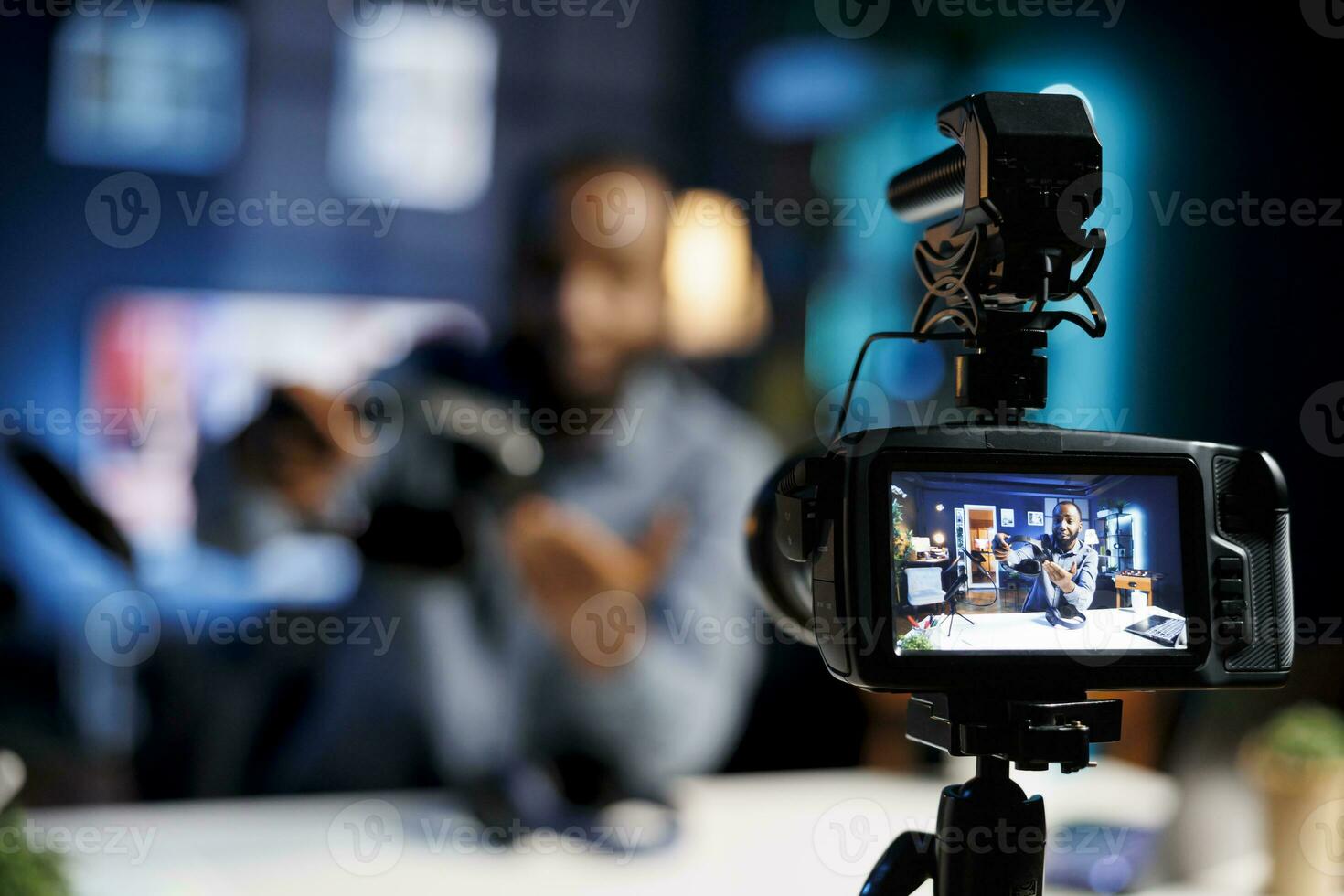 focus Aan professioneel video productie uitrusting gebruikt voor vastleggen beeldmateriaal van internet tonen gastheer in wazig achtergrond filmen tech beoordelingen voor zijn online kanaal, presentatie van stereo hoofdtelefoons foto