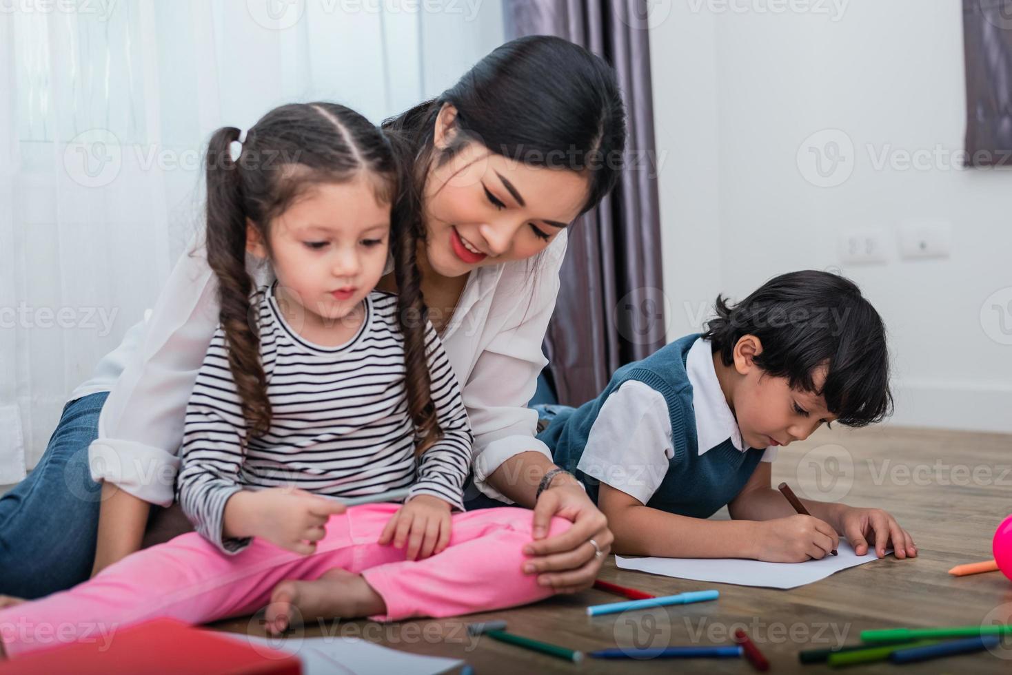 moeder die kinderen lesgeeft in de tekenles. dochter en zoon schilderen met kleurrijke krijtkleur in huis. lerarenopleiding studenten in kunst klas. onderwijs en leerontwikkeling van thema voor kinderen foto