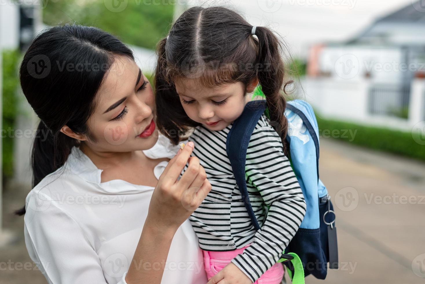 moeder voedt haar dochter met een snack voordat ze naar school gaat. terug naar school en onderwijsconcept. home sweet home en happy family thema foto