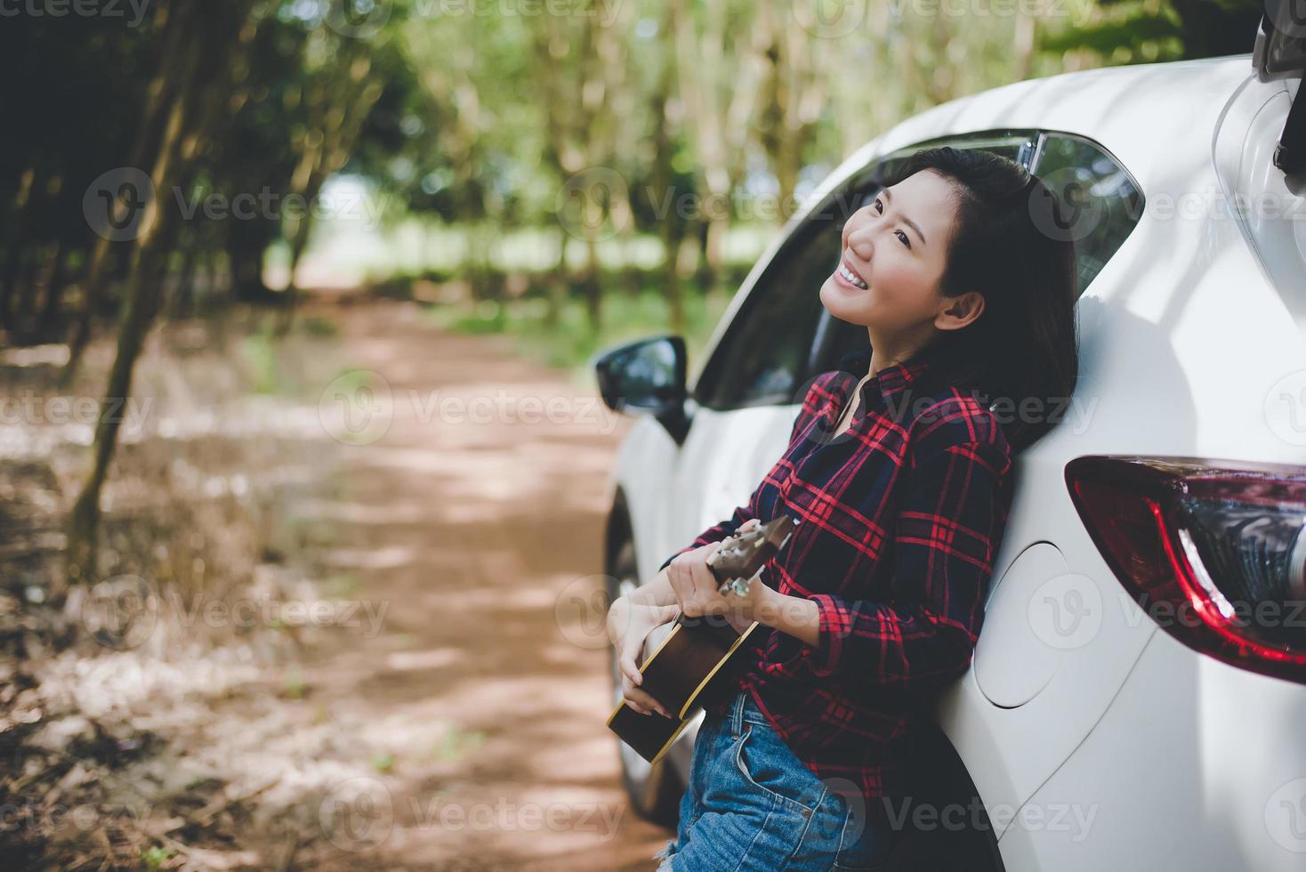 schoonheid Aziatische vrouw glimlachend en plezier buitenshuis zomer met ukelele in de buurt van witte auto. reizen van fotograaf concept. hipster-stijl en solo-vrouwenthema. levensstijl en geluk leven thema foto