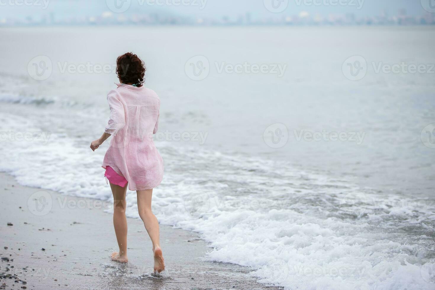 een middelbare leeftijd vrouw loopt langs de kust. foto