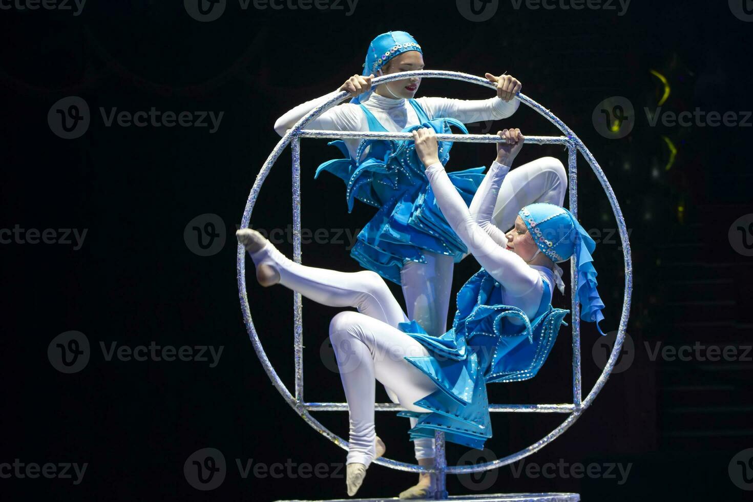 twee acrobaat meisjes tonen een circus aantal Aan een donker achtergrond. acrobatisch prestatie. foto