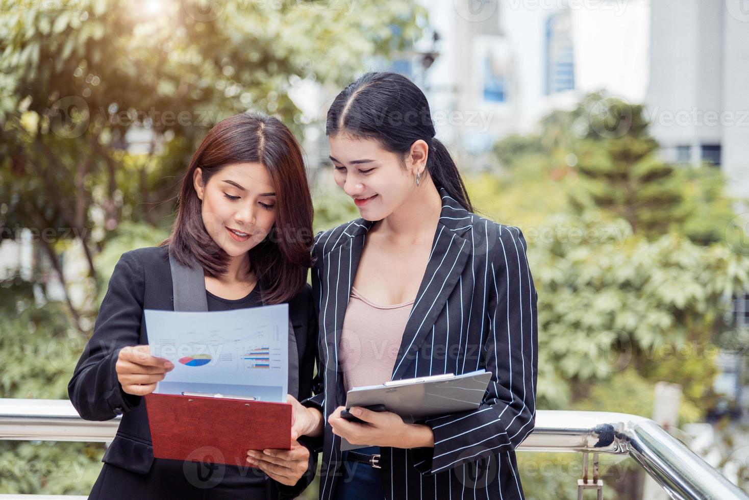 twee jonge aziatische zakenvrouwen op zoek naar documentbestandsmap voor het analyseren van winst of verkoop break-even point na marketing. zakelijke teamwerk medewerkers van lifestyle werkende vrouwen concept foto