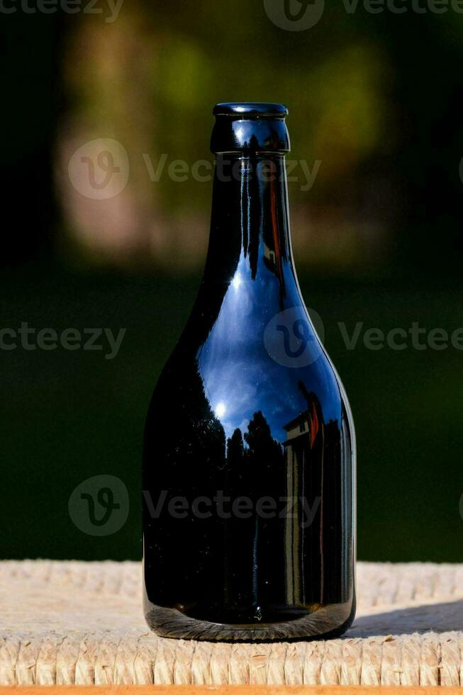 een zwart fles zittend Aan een houten tafel foto