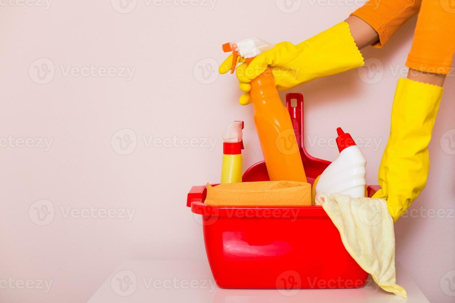 huisvrouw nemen mand met schoonmaak uitrusting van tafel en voorbereidingen treffen voor schoonmaak. foto