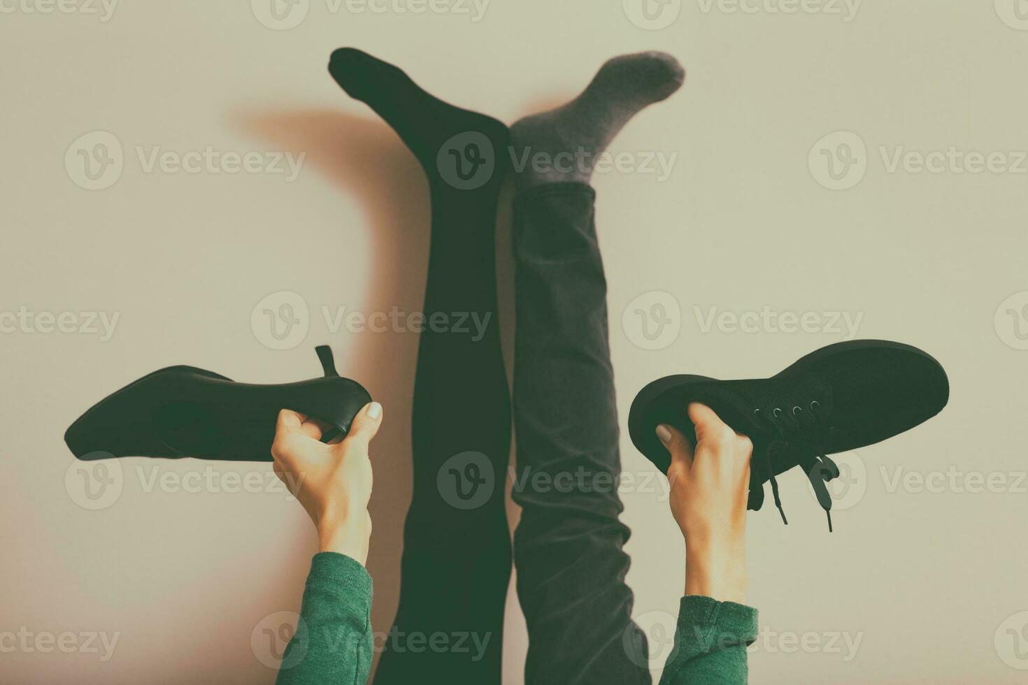 poten van een vrouw in zwart panty en jeans Holding sport schoen en hoog hakken.afgezwakt foto. foto